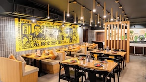 L’intérieur d’un restaurant, avec des banquettes, des tables et des luminaires suspendus.