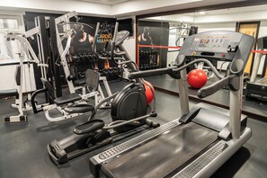 Uma academia com máquinas de cardio, halteres e esteira.