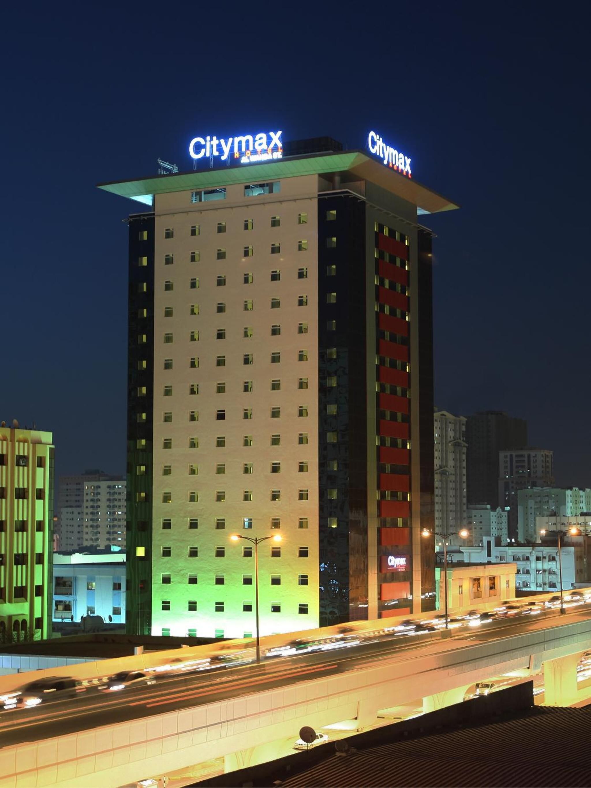Un hotel alt amb la senyalització 'Citymax', nombroses plantes i una vista del paisatge urbà al fons.
