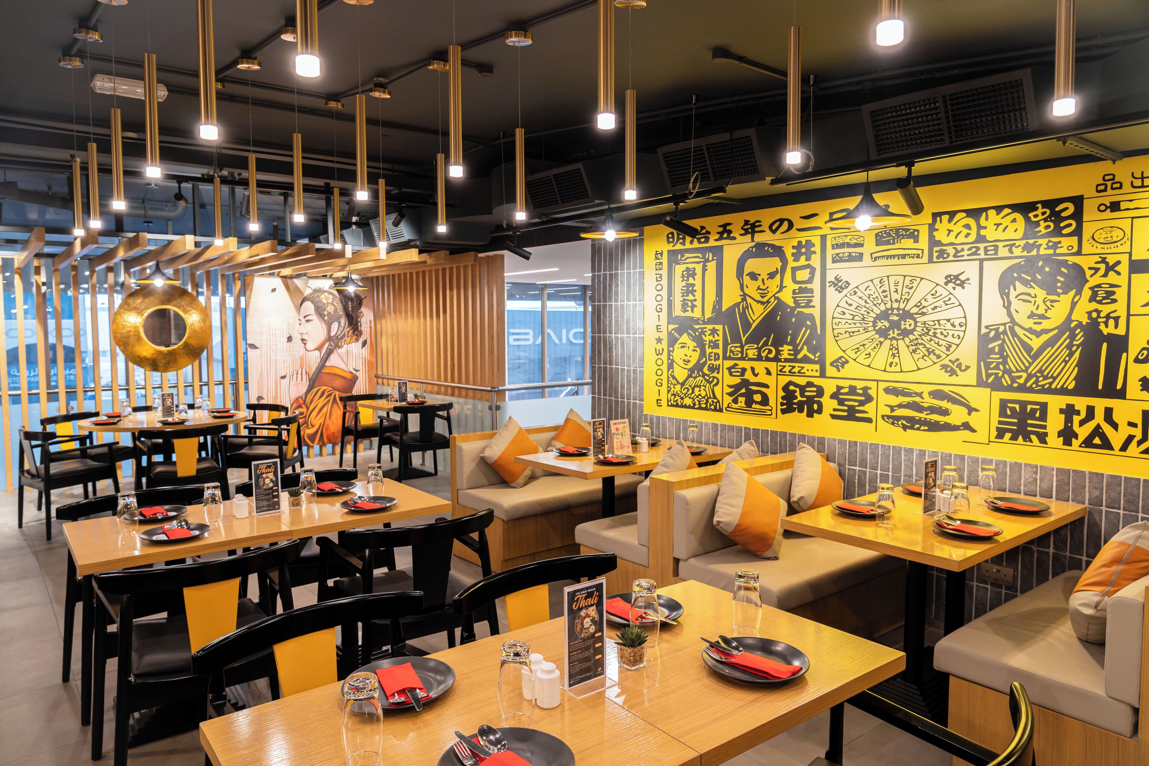 Interior de restaurante con mesas, sillas y una pared decorada con motivos asiáticos.