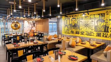 Interior de restaurante con mesas, sillas y una pared decorada con motivos asiáticos.