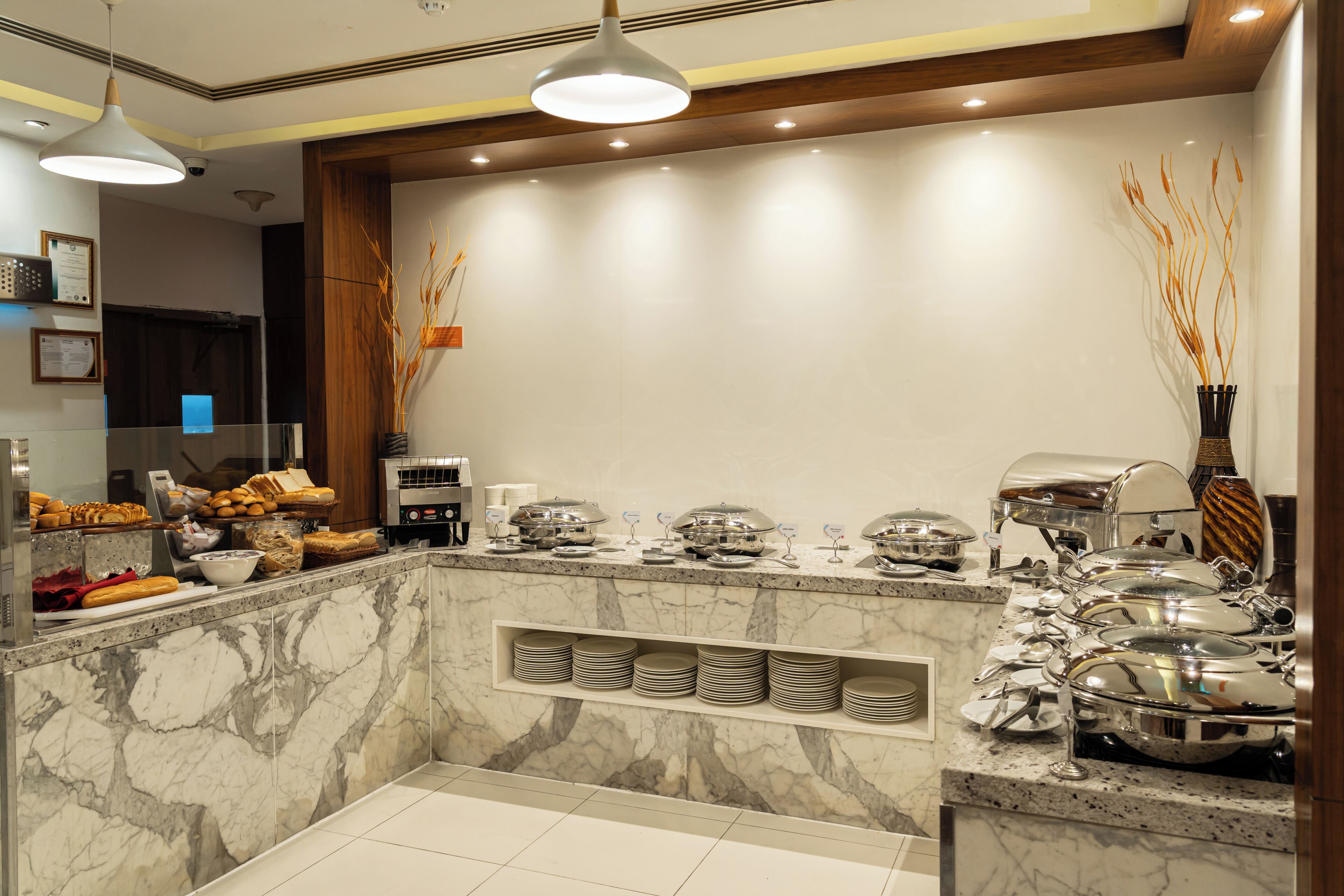 A buffet area with marble countertops, stainless steel serving dishes, and a variety of food items.