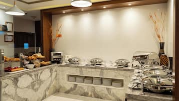 A buffet area with marble countertops, stainless steel serving dishes, and a variety of food items.
