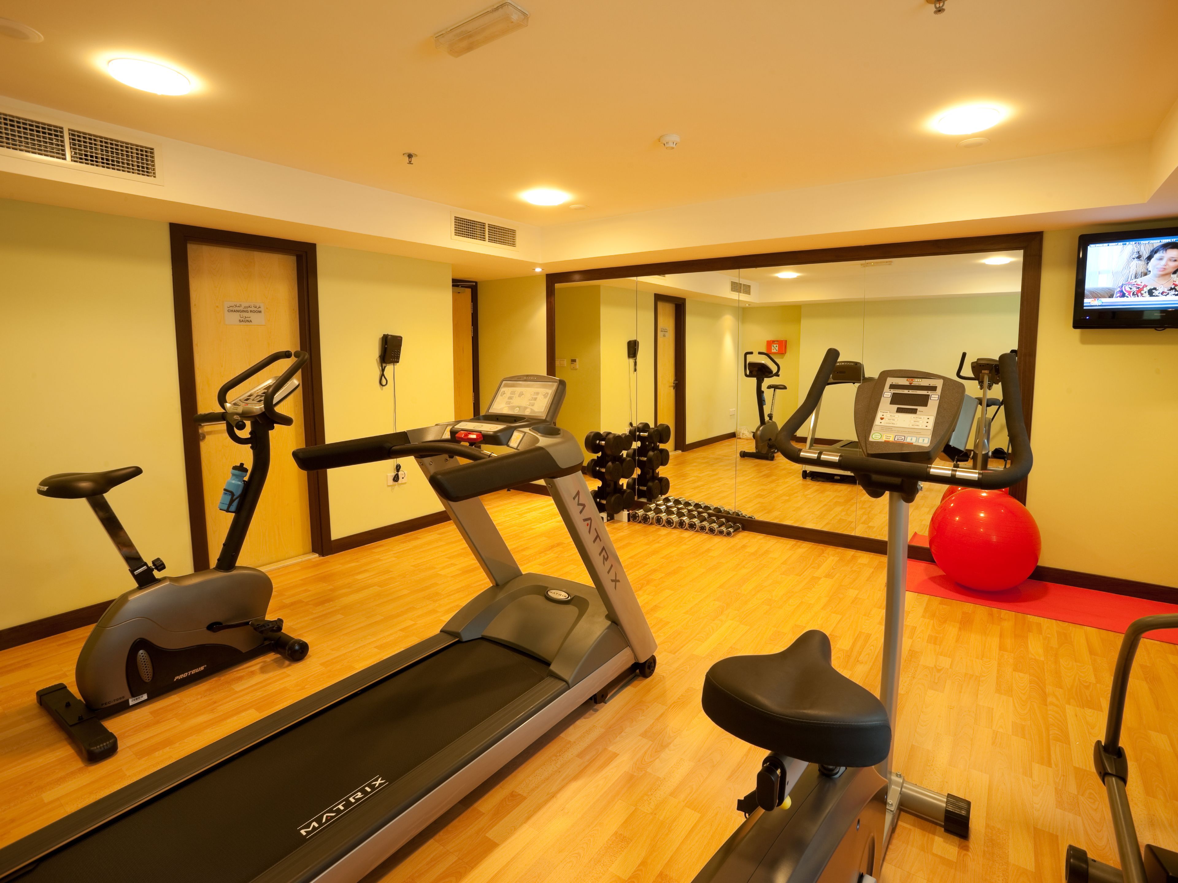 Un gimnasio con cintas de correr, bicicletas estáticas y pesas sueltas.