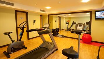 Un gimnasio con cintas de correr, bicicletas estáticas y pesas sueltas.