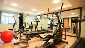Une salle de sport équipée de machines de cardio, de poids libres et de ballons d’exercice.