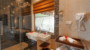 Un baño moderno con cabina de ducha de vidrio, un lavamanos amplio con espejo y un perchero con toallas dobladas con esmero.