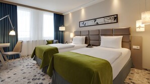A hotel room with two beds, a desk, and a chair. - Holiday Inn Berlin - City East Side by IHG (Berlin)