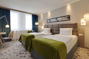 A hotel room with two beds, a desk, and a chair. - Holiday Inn Berlin - City East Side by IHG (Berlin)