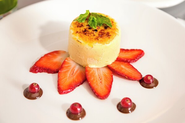 Un postre sobre un plato blanco, con fresas y puntos de chocolate.