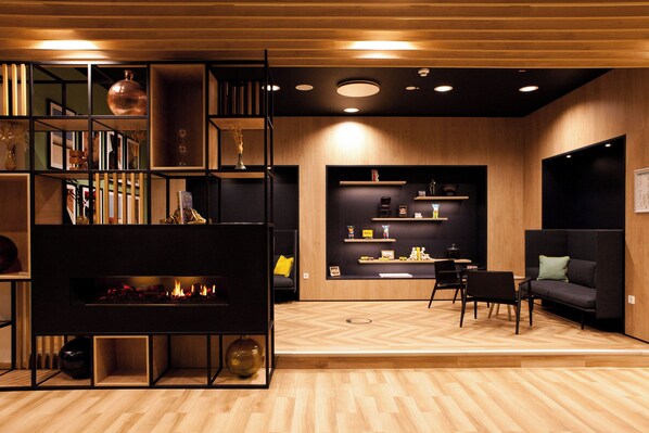 A modern living room with a fireplace, wooden flooring, and a black sectional sofa.