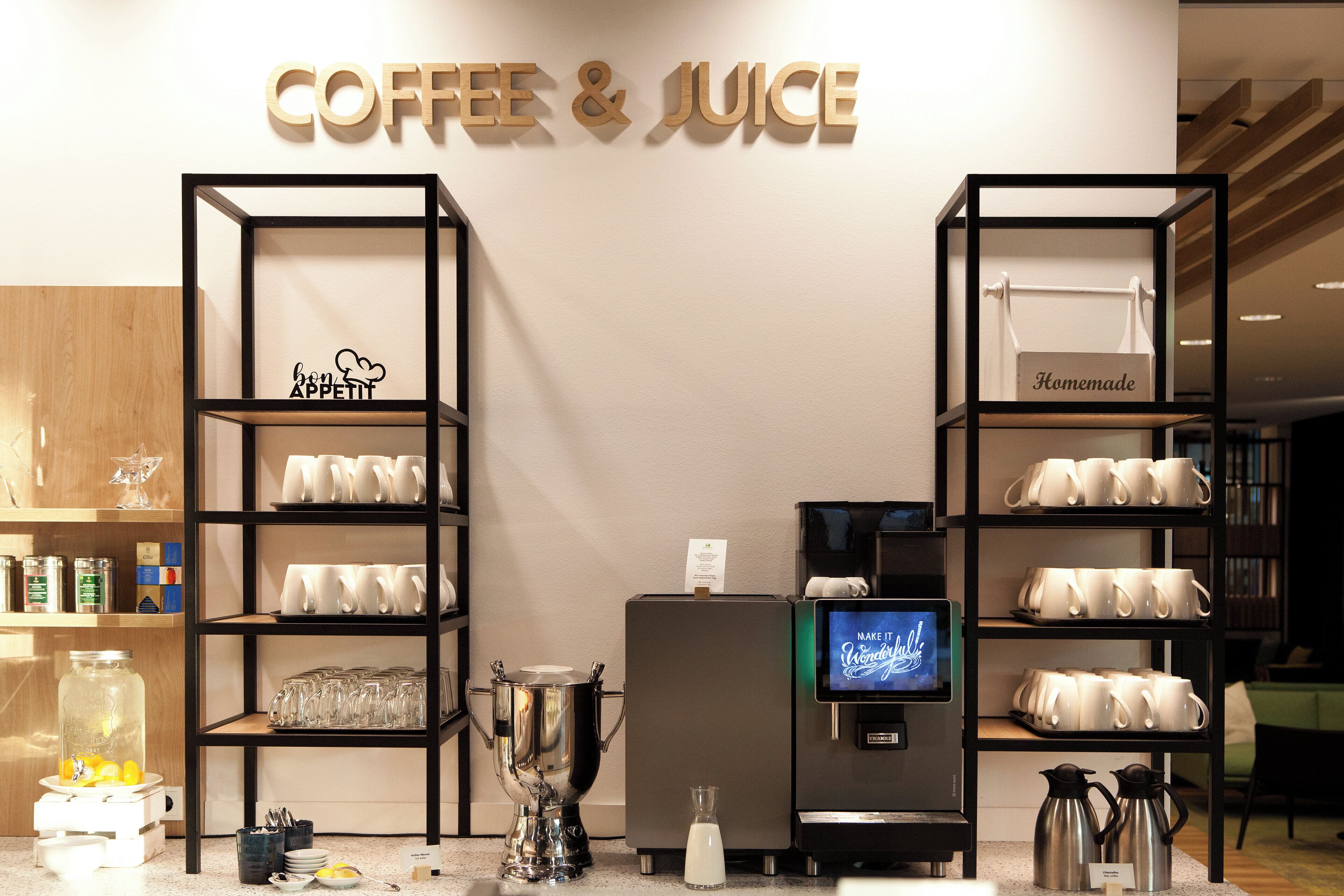 A coffee and juice station with shelves of mugs and a coffee machine.