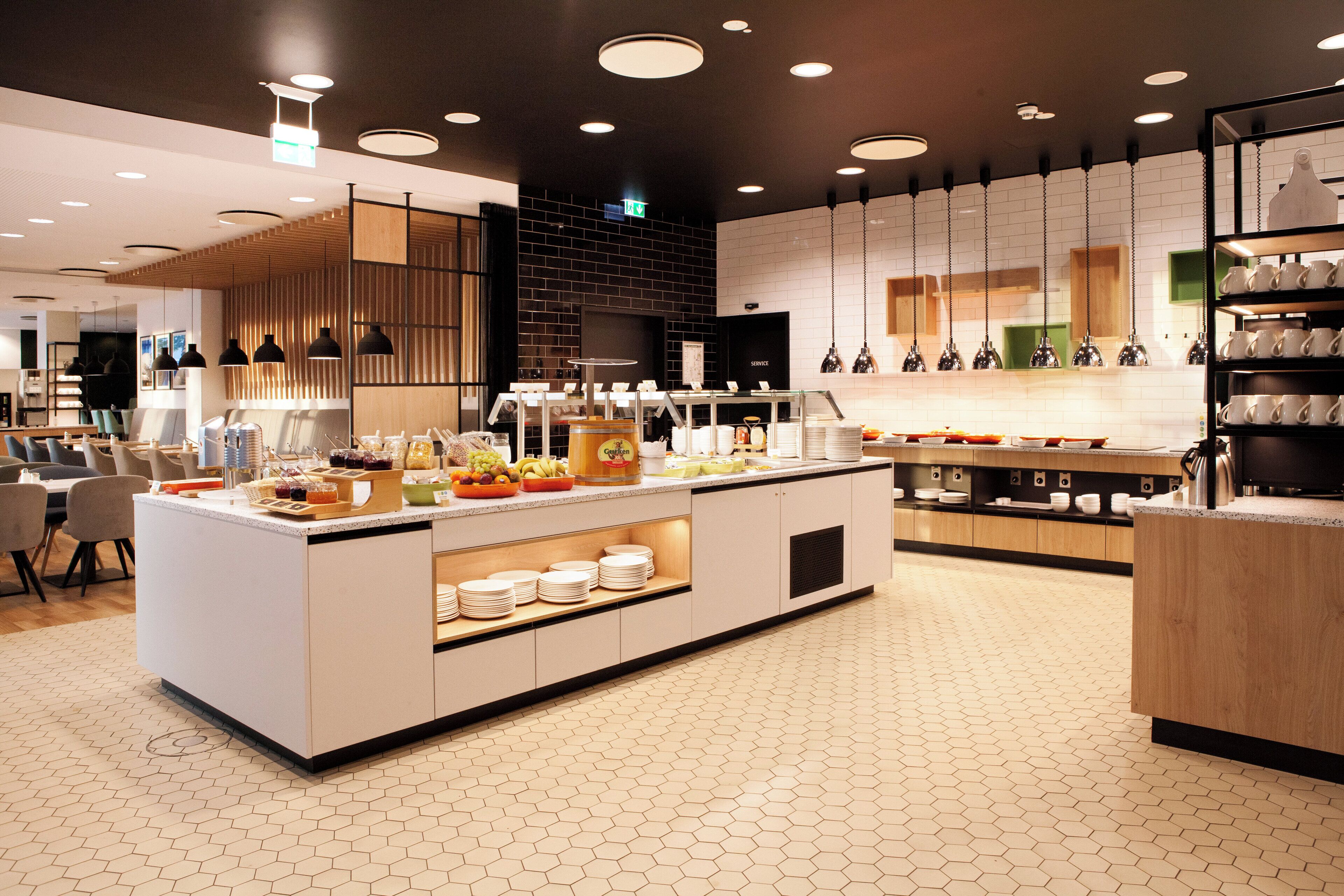 A modern kitchen with a central island, equipped with various appliances and a buffet setup.