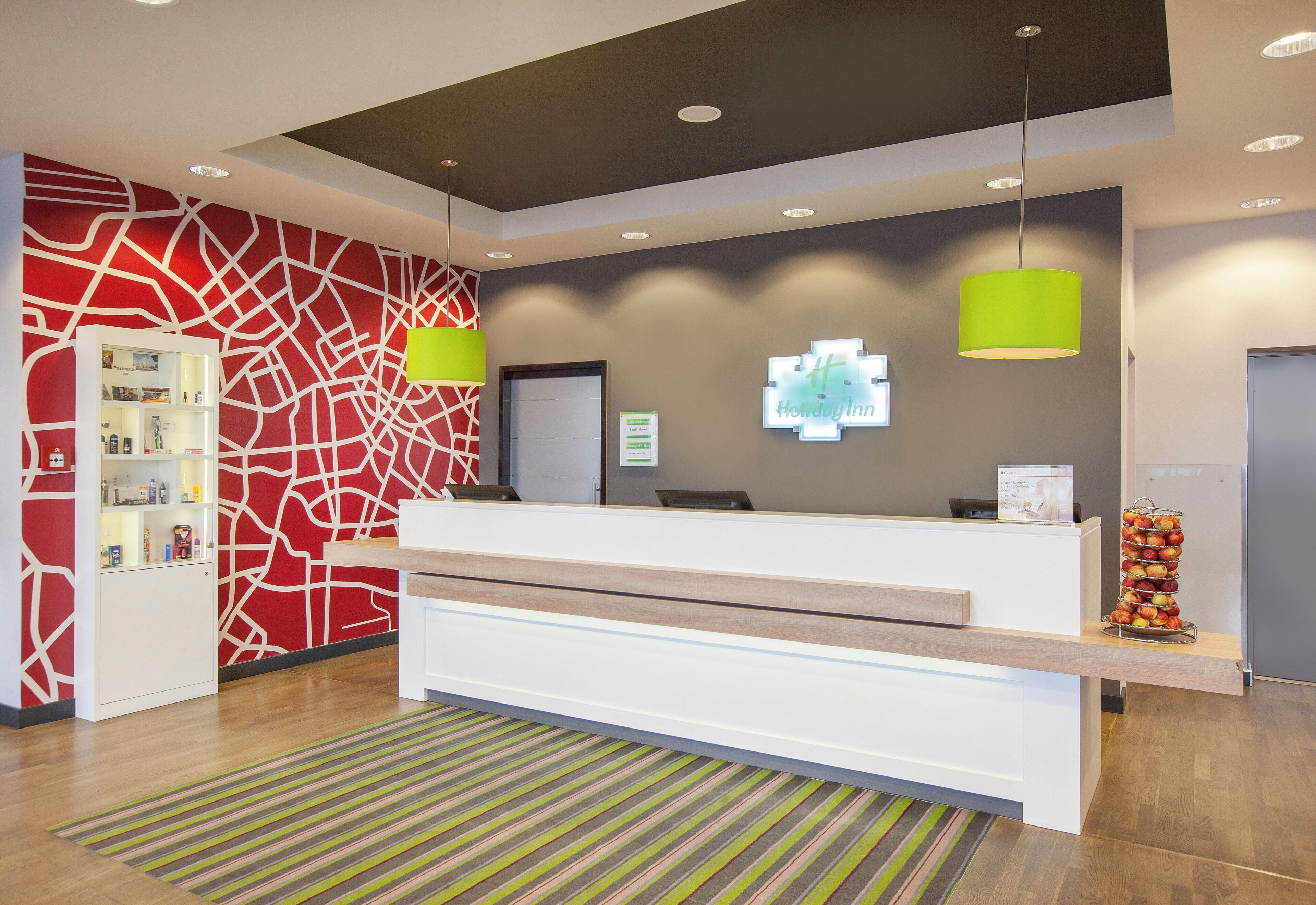A reception desk with a modern design, a digital display, and a fruit stand.