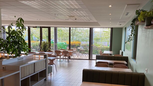 A restaurant with a modern interior, large windows, and a mix of seating options including tables and booths. - Ibis Styles Flers (Flers)