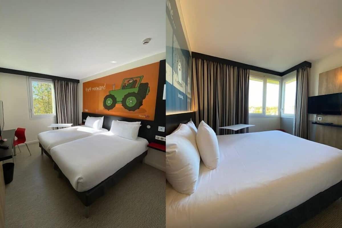 A hotel room with two beds, a TV, a desk, and a large window with curtains.