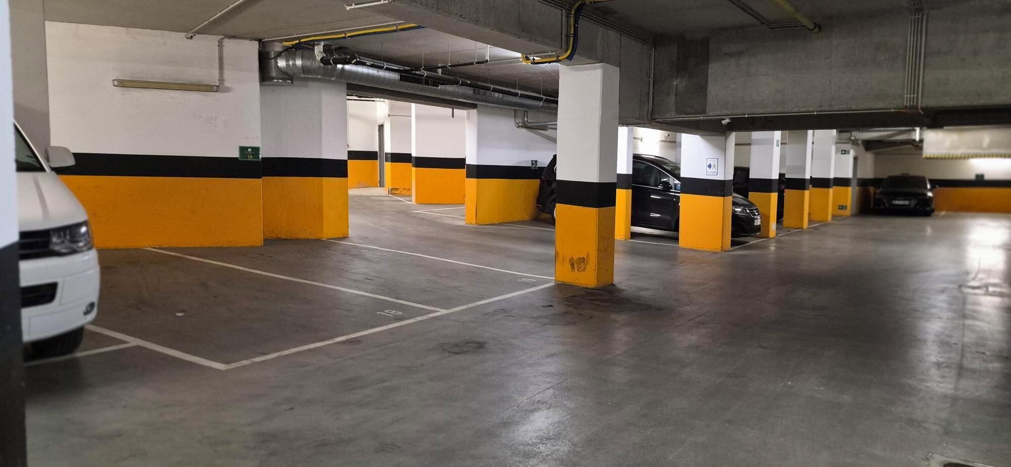 A multi-level parking garage with concrete floors and yellow and black pillars.