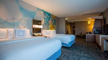 A hotel room with two beds, a desk, a chair, a TV, and a microwave.