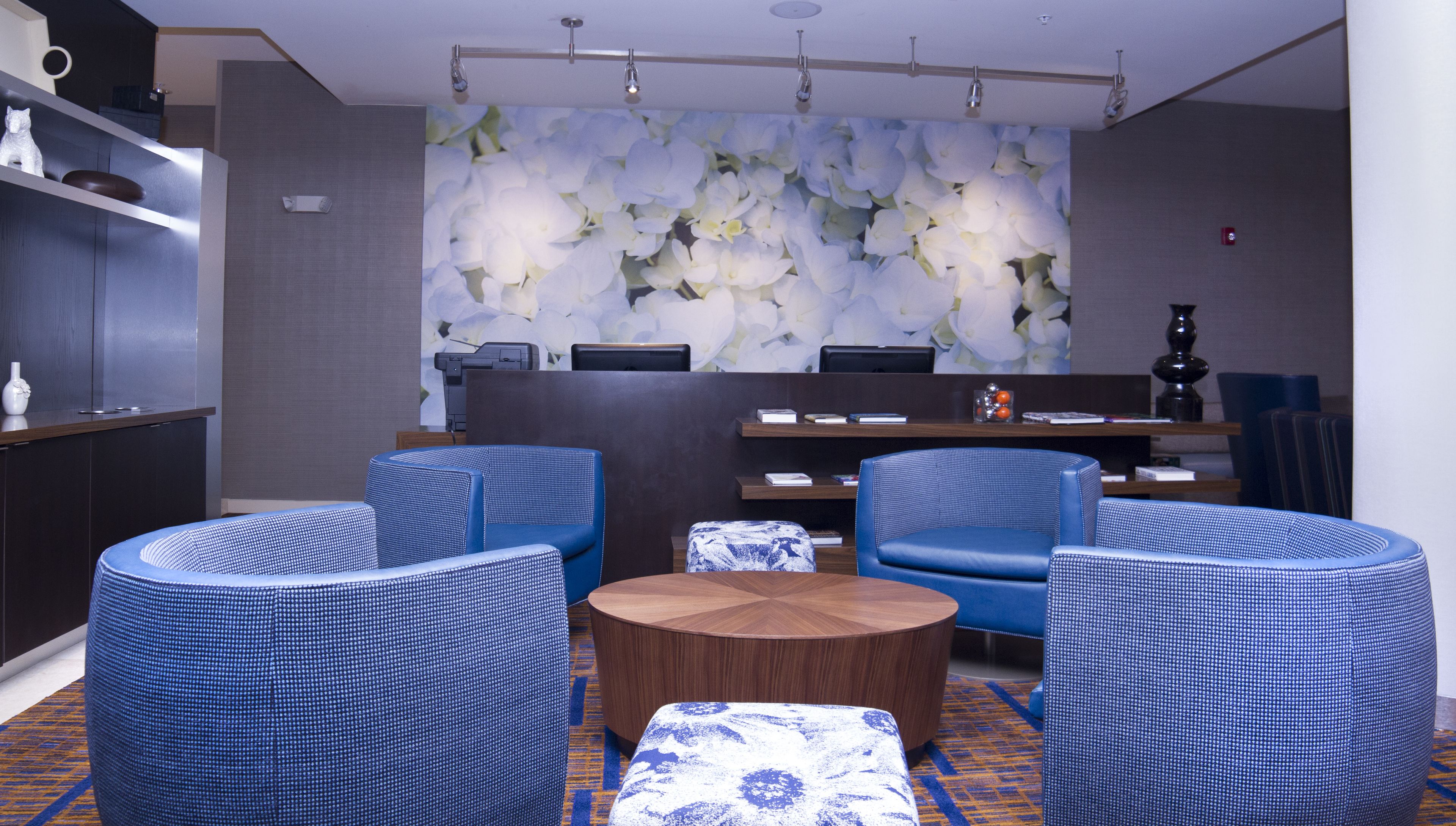 Een moderne lobby met blauw gestreept zitmeubilair, een houten bijzettafeltje en bloemenbehang.