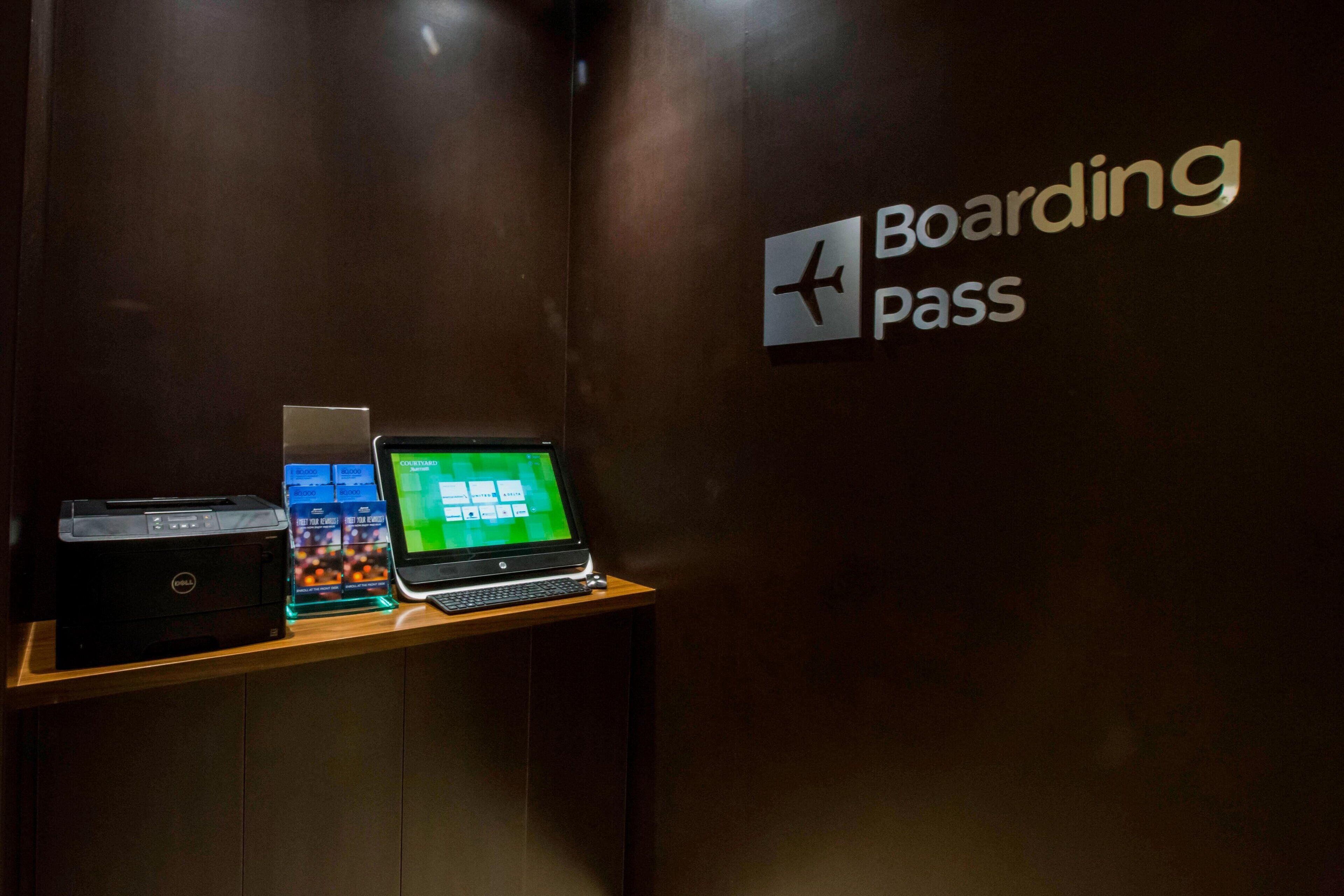 A wooden counter with a Dell printer, a laptop, and a sign for 'Boarding Pass'.