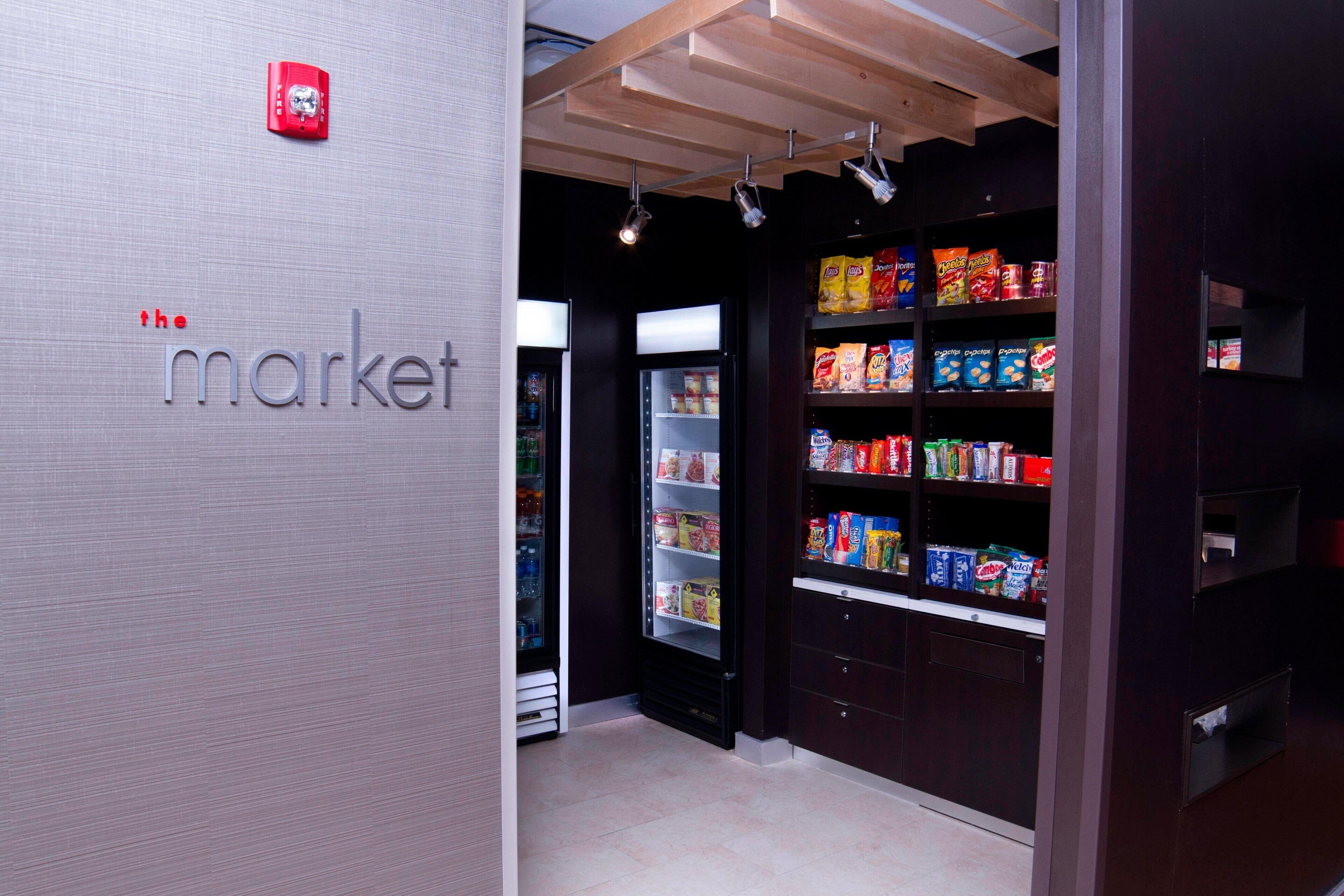 A store interior with shelves stocked with various products, a refrigerated section, and a sign reading "the market".