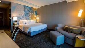 Ein Hotelzimmer mit einem großen Bett, einer Couch, einem Schreibtisch und einer Lampe.