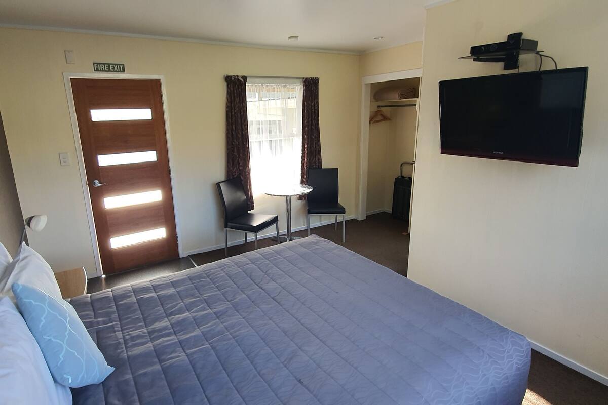 Una habitación de hotel con cama, televisión, escritorio y armario.