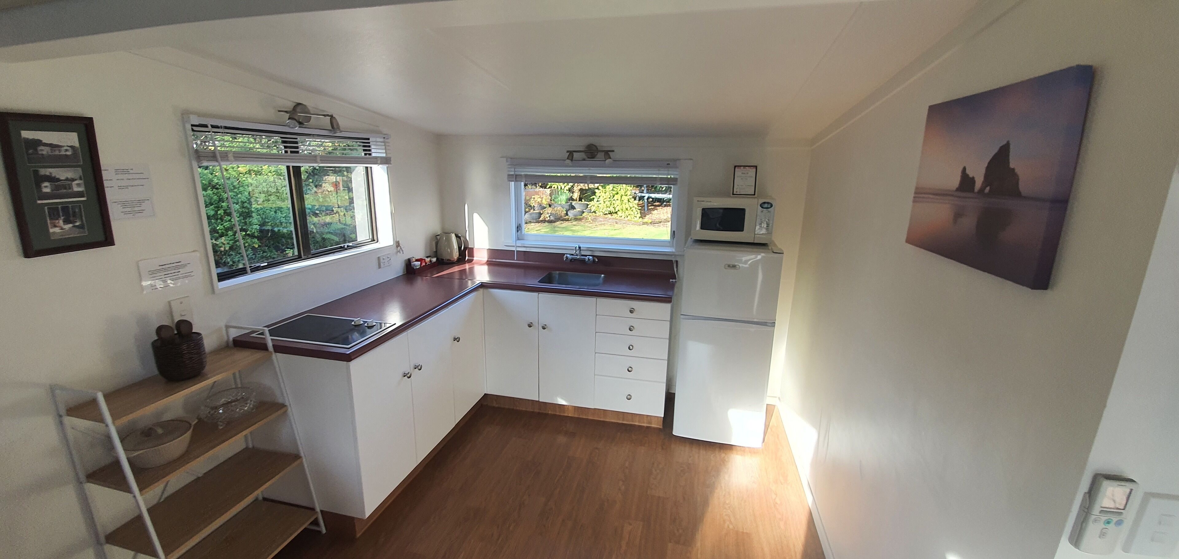Una cocina compacta con armarios blancos, encimera de madera, microondas y un lavabo.