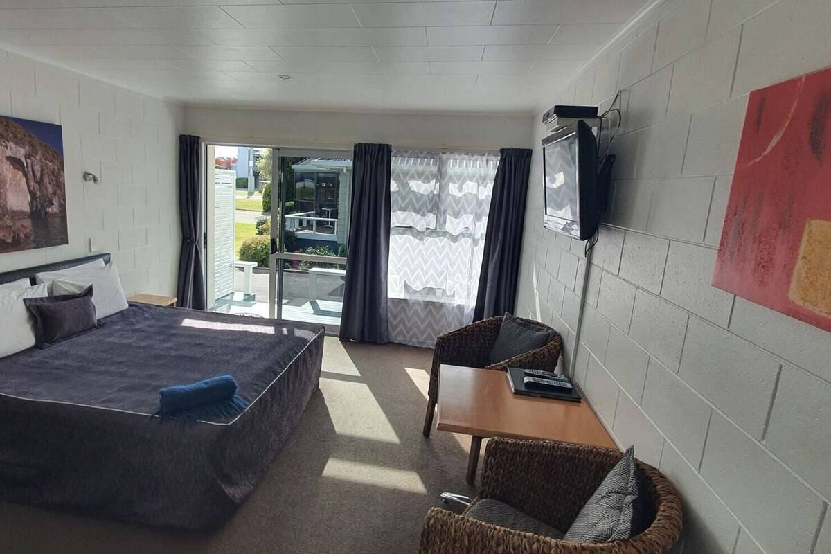 Un dormitorio con una cama, un escritorio, una silla, un televisor y un cuadro en la pared.