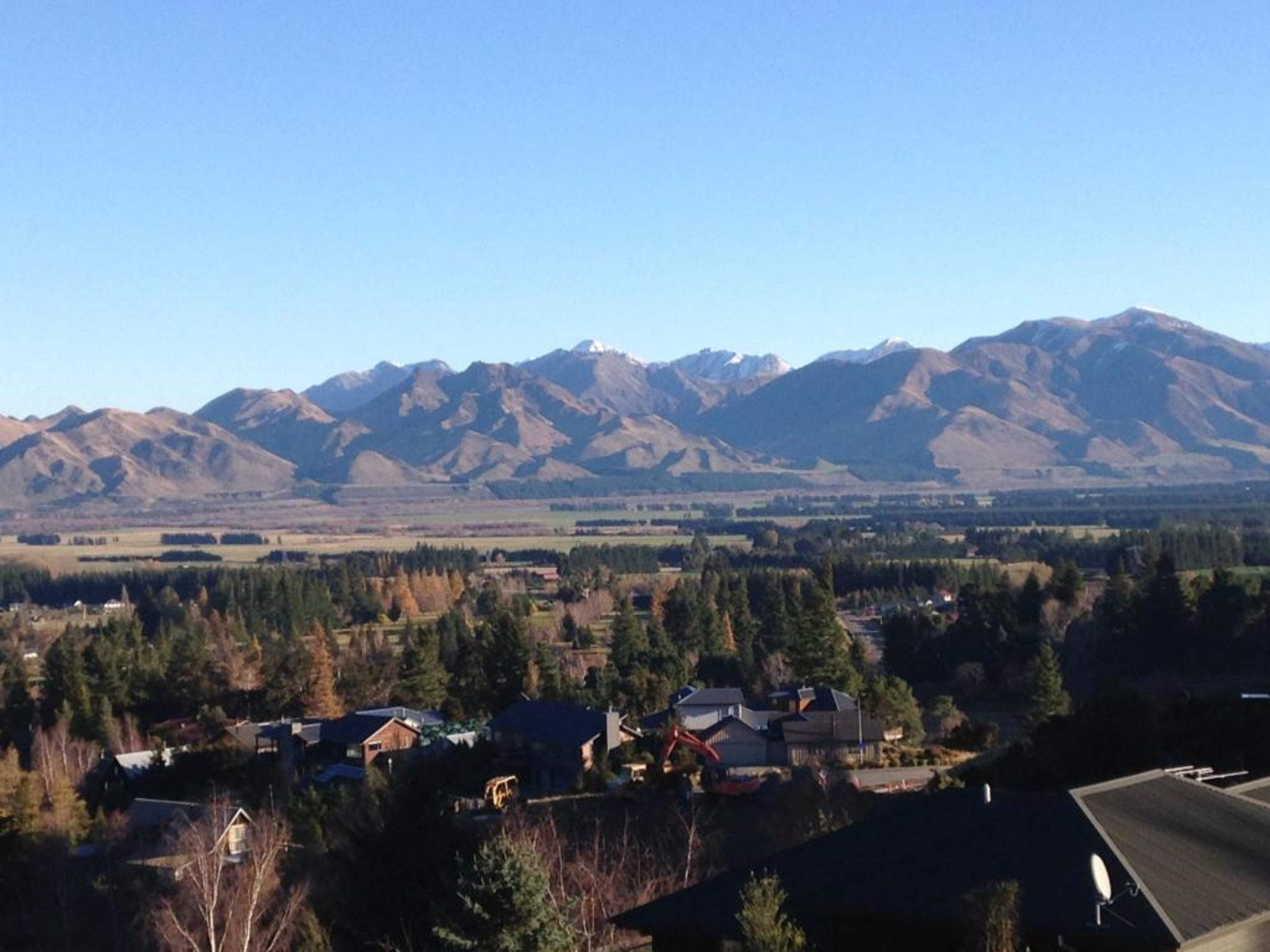 A residential area with houses and a mountain range in the background.
