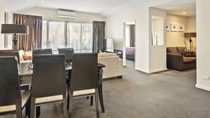 A spacious living area with a dining table, chairs, a sofa, and a television.