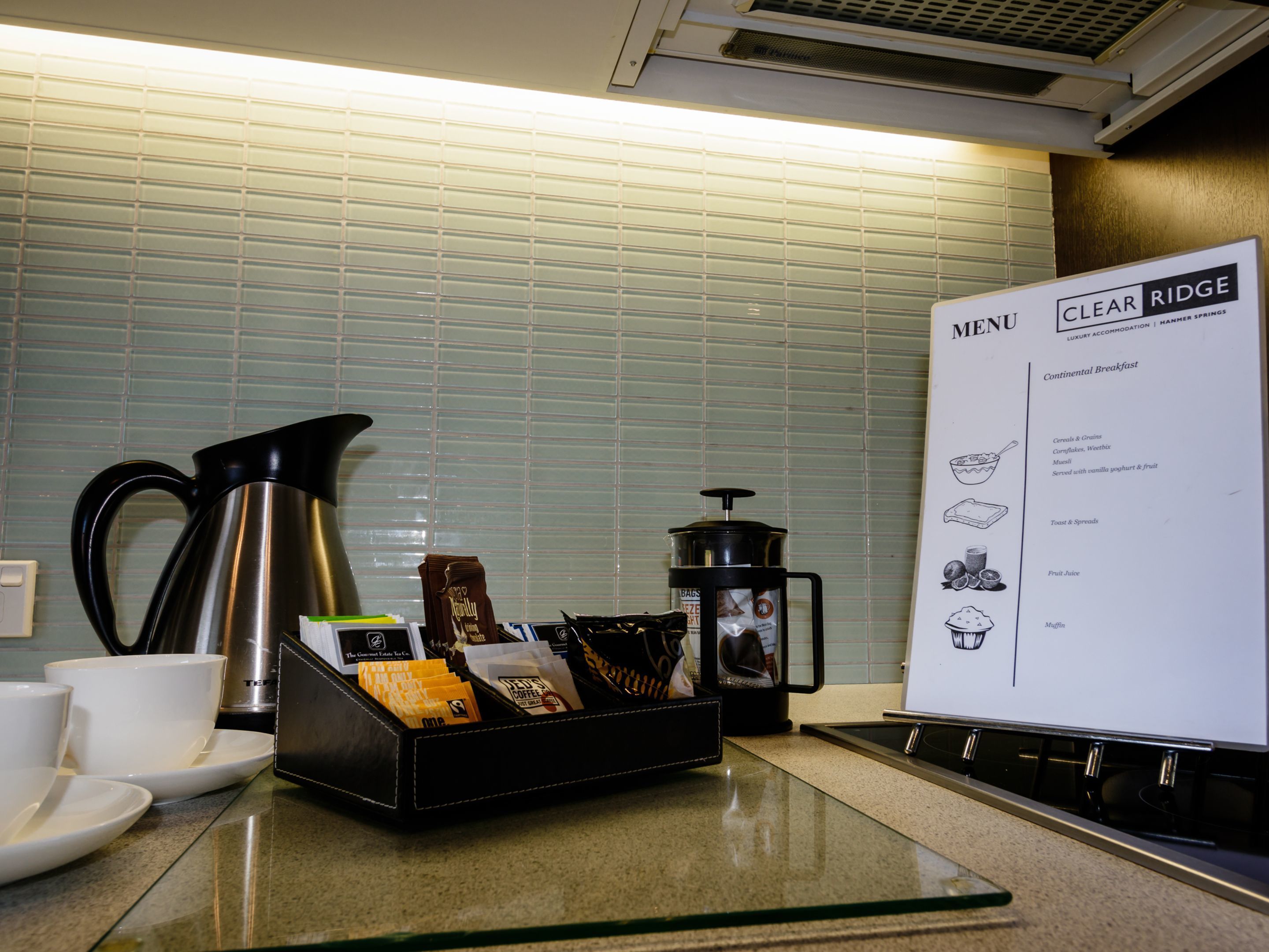 A kitchen counter with a coffee maker, a milk carton, and a menu board.