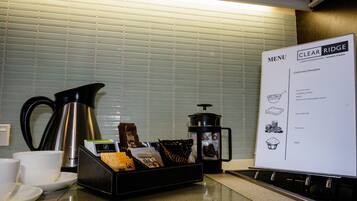 A kitchen counter with a coffee maker, a milk carton, and a menu board.