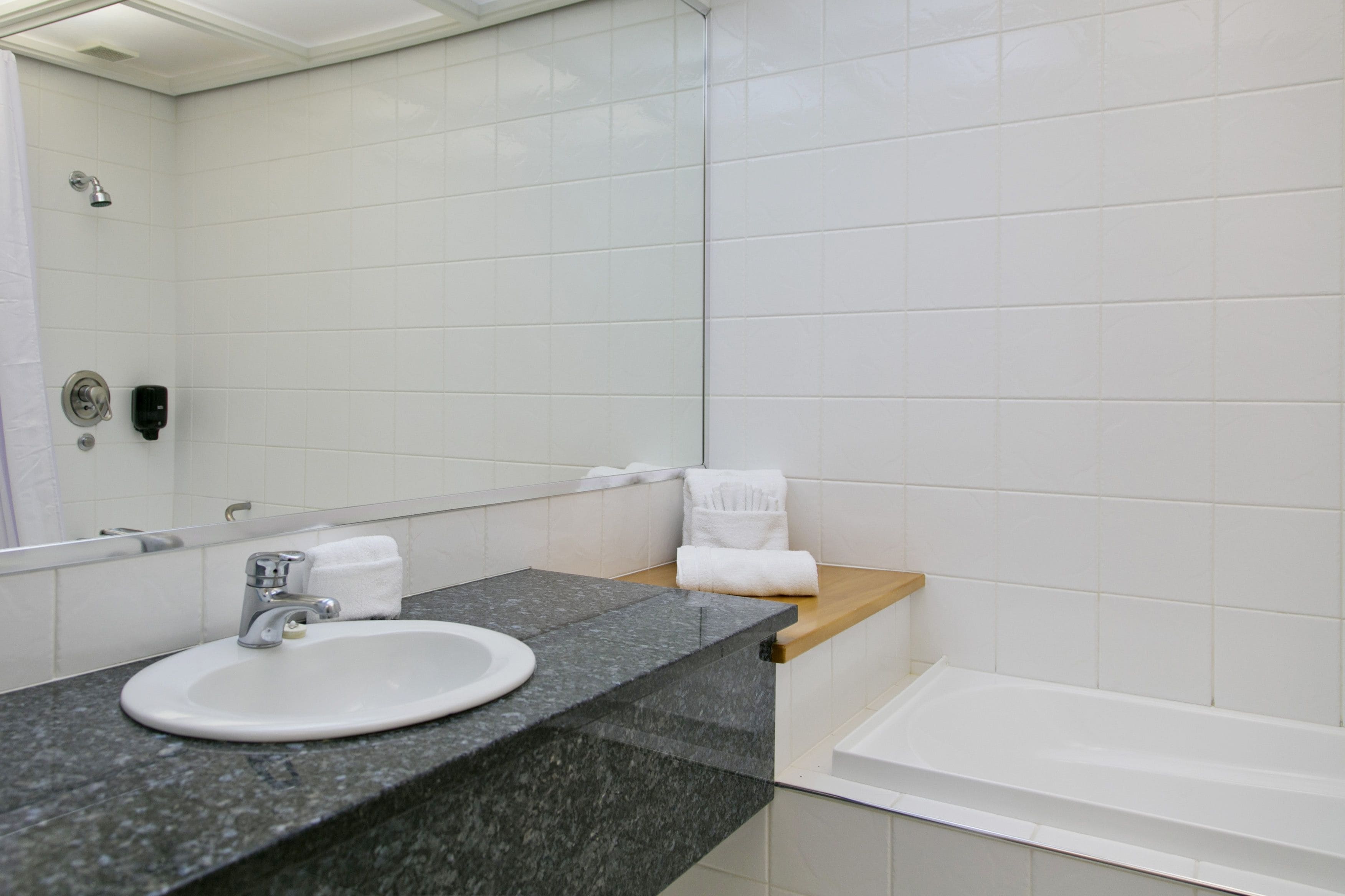 A bathroom with a white sink, a mirror, a towel rack, and a bathtub.