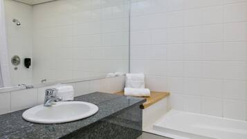 A bathroom with a white sink, a mirror, a towel rack, and a bathtub.