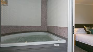 A room with a bathtub, a bed, and a small window.