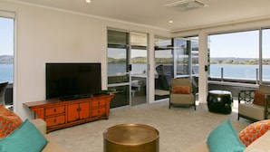 Een moderne woonkamer met een grote flatscreen-televisie, een houten kast en een ronde salontafel.