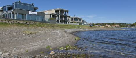 Een kustpand met moderne architectuur, een strand en uitzicht op zee.