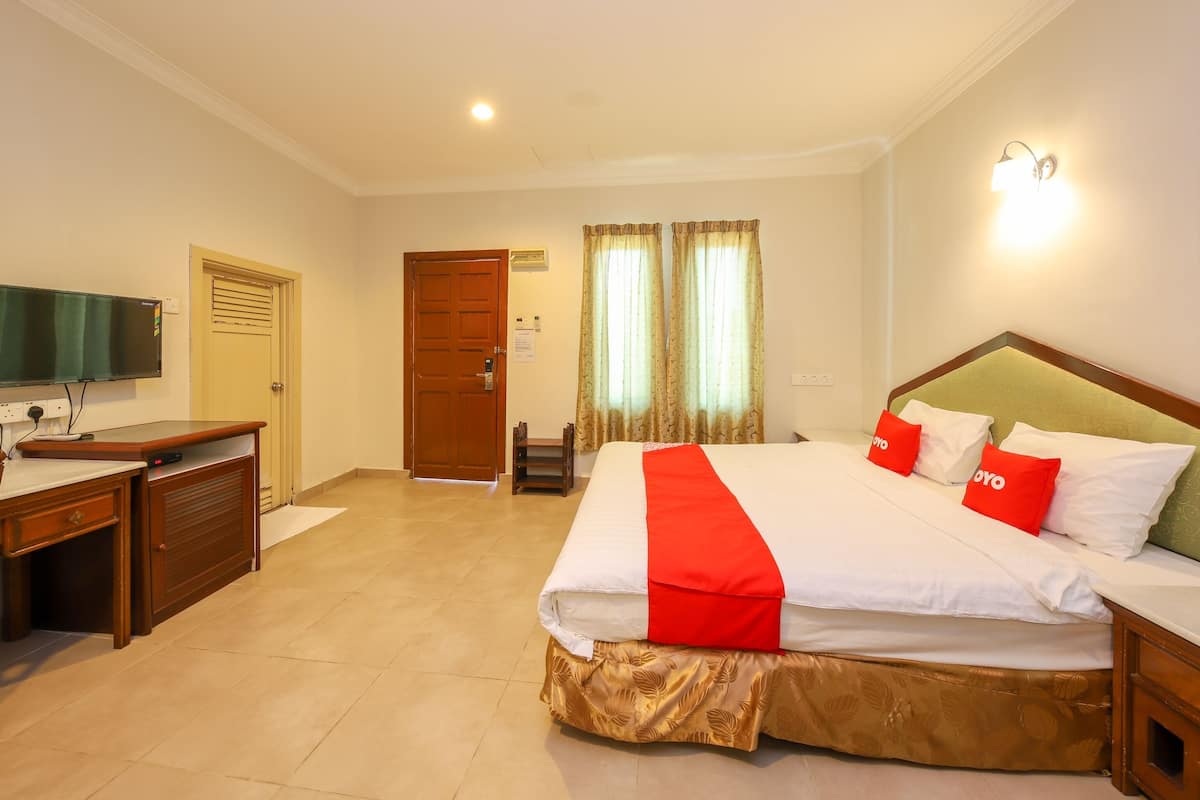 Habitación de hotel con cama, escritorio, televisión y cortinas.