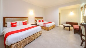 Une chambre d’hôtel avec deux lits, un bureau, une chaise et un téléviseur.
