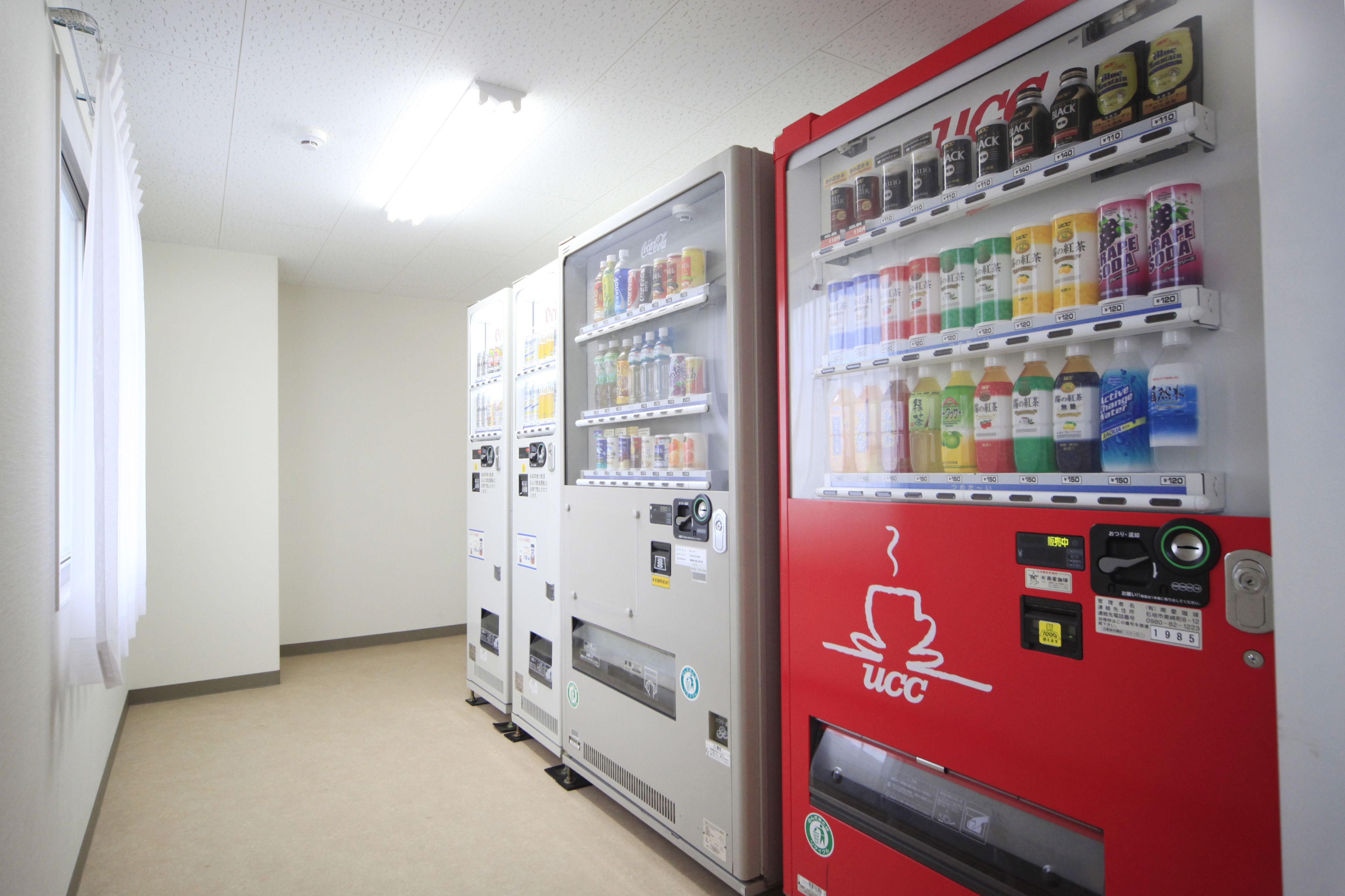 Une rangée de distributeurs automatiques dans un couloir, avec un mur blanc uni et un sol recouvert de moquette.