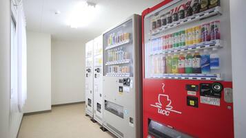 Une rangée de distributeurs automatiques dans un couloir, avec un mur blanc uni et un sol recouvert de moquette.