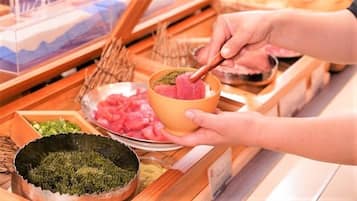 A person preparing a dish with a bowl of pinkish food, possibly sashimi, and a wooden spoon.