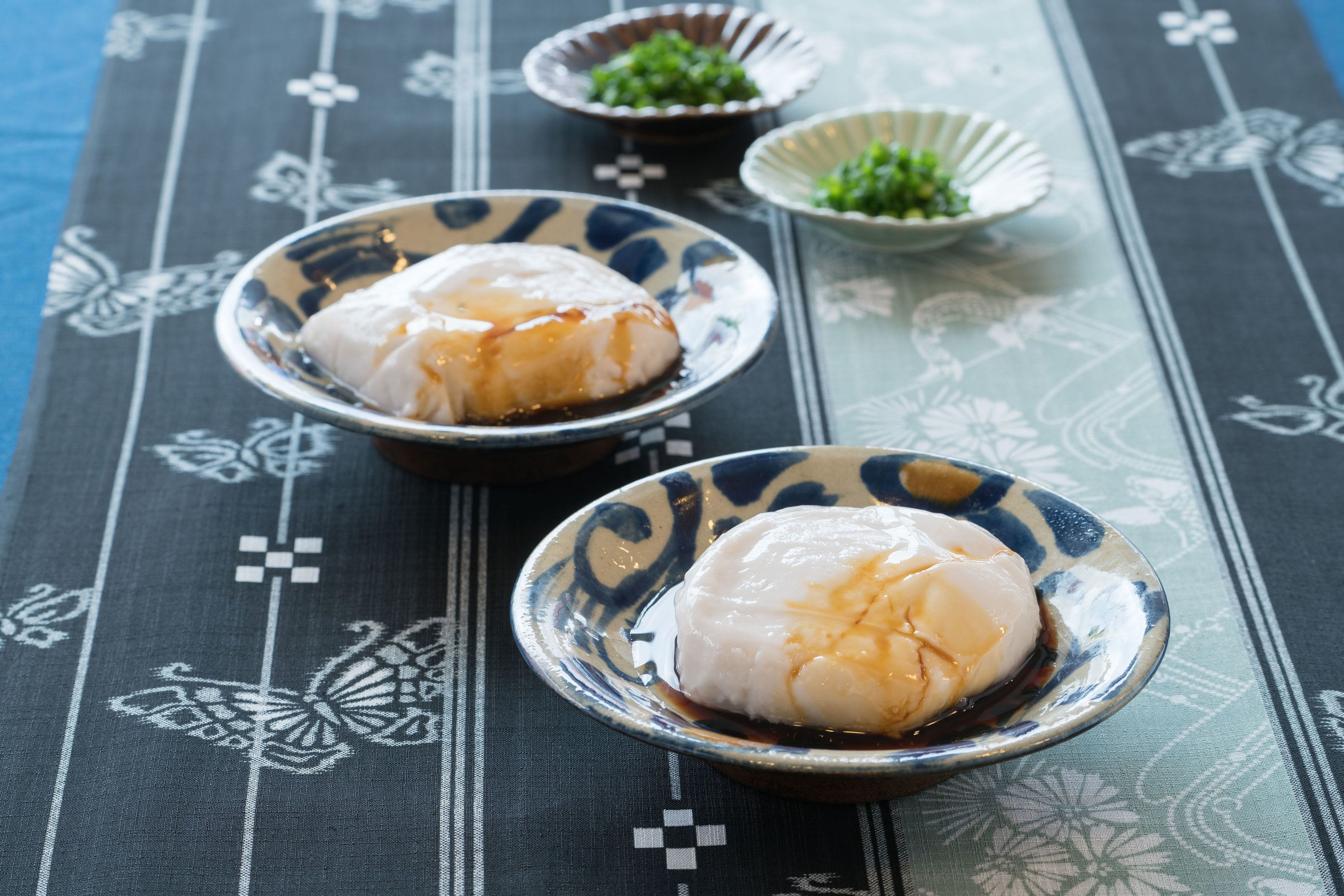 Three bowls of food on a table with a patterned tablecloth.