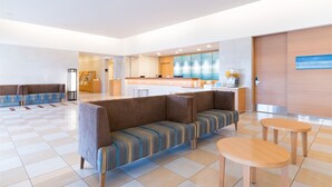 A modern hotel lobby with a checkered floor, a seating area with a sofa and armchairs, and a small table.