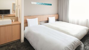 A hotel room with a bed, a TV, a sink, and a mirror.