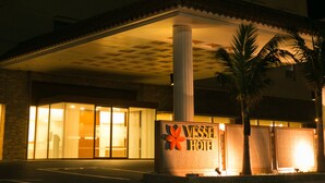 A hotel entrance with a sign reading "Vessel Hotel," a covered entrance area, and palm trees.