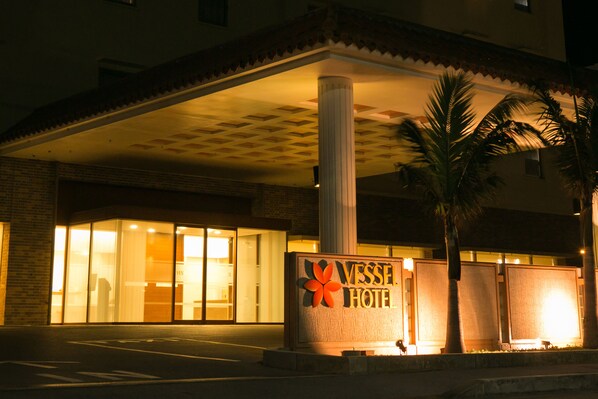 A hotel entrance with a sign reading "Vessel Hotel," a covered entrance area, and palm trees.