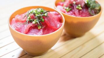 Deux bols de sashimi garnis d’oignons verts, posés sur une surface en bois.