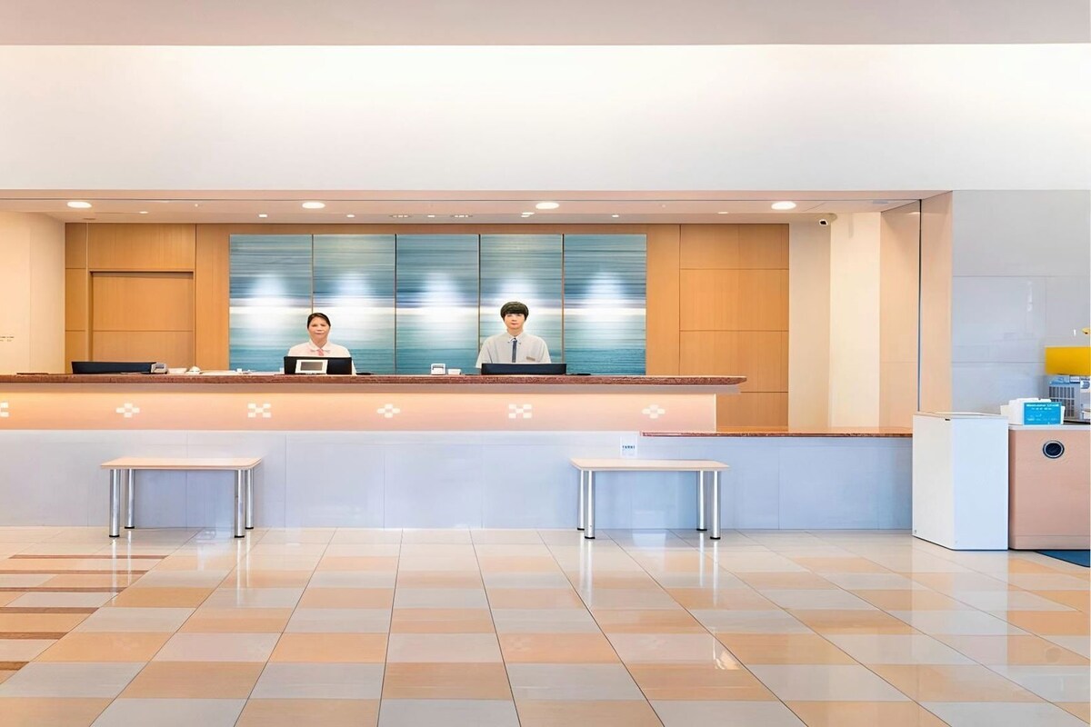 Een hotel receptie met een incheckbalie, twee receptionisten en een modern ontwerp.